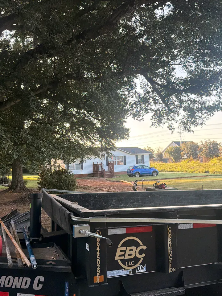 EBC Construction branded dump trailer beside a prepared residential work site.