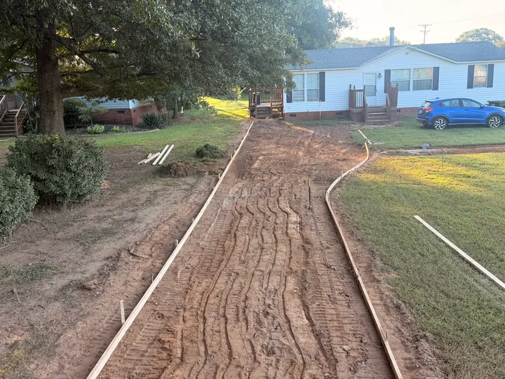 Shaped soil base inside curved driveway forms before concrete placement.