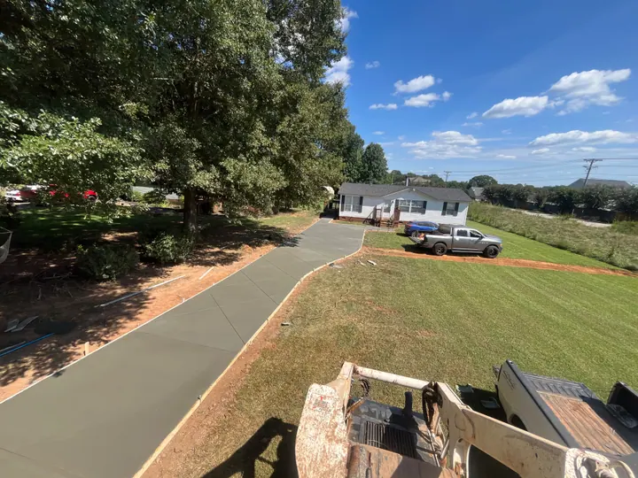 Wide view of a newly placed residential concrete approach with diagonal joints and curved edges.